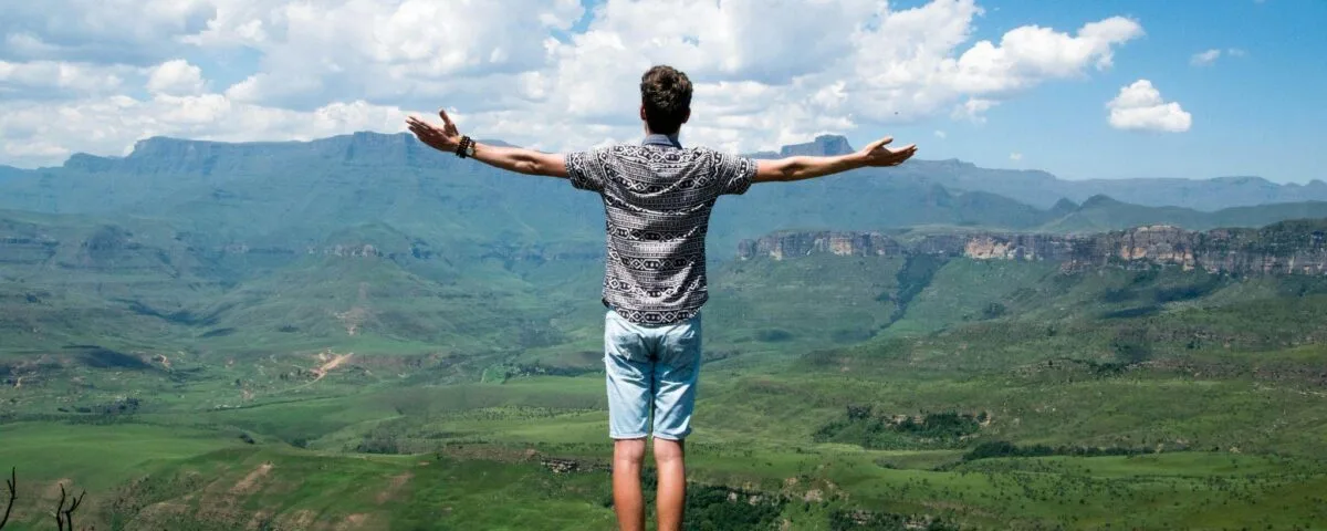 muz-s-roztaženýma-rukama-na-kopci-nad-krajinou